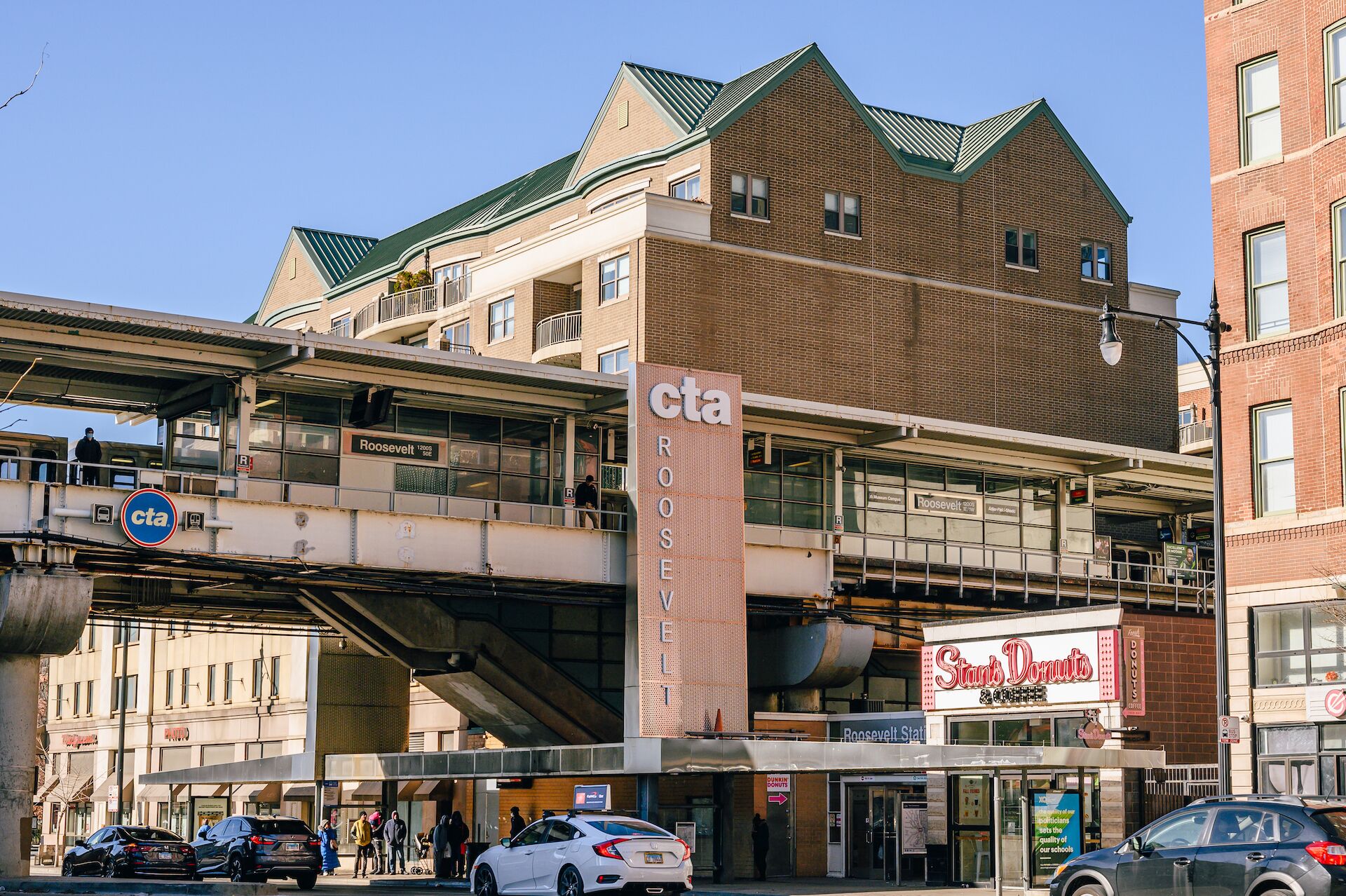 A multi-story building with a CTA station sign, a Roosevelt Street sign, and a Stans Donuts store.