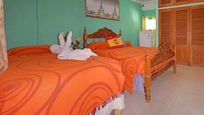 Ein Schlafzimmer mit einem Bett, einem Bild vom Eiffelturm, einem Holzschrank und einem Ventilator.
