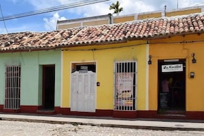 A building with a tiled roof, a yellow facade, and a sign for 'La Cecilia' indicating a hostel. - Casa la espagnola (Trinidad)