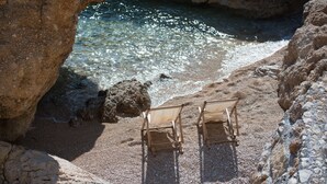 A beach with two wooden chairs and a rocky shoreline. - Apartments Andrea (Omis)