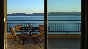 A balcony with a table set for two, overlooking a body of water and distant mountains. - Apartments Andrea (Omis)