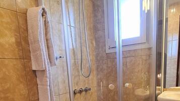 Un baño con ducha de vidrio, inodoro y lavamanos.