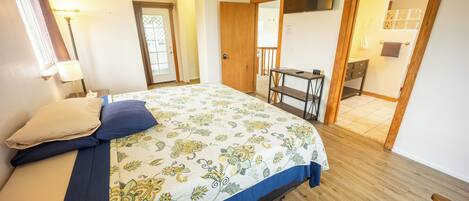 Un dormitorio con una cama, un escritorio y un baño visible a través de una puerta abierta.