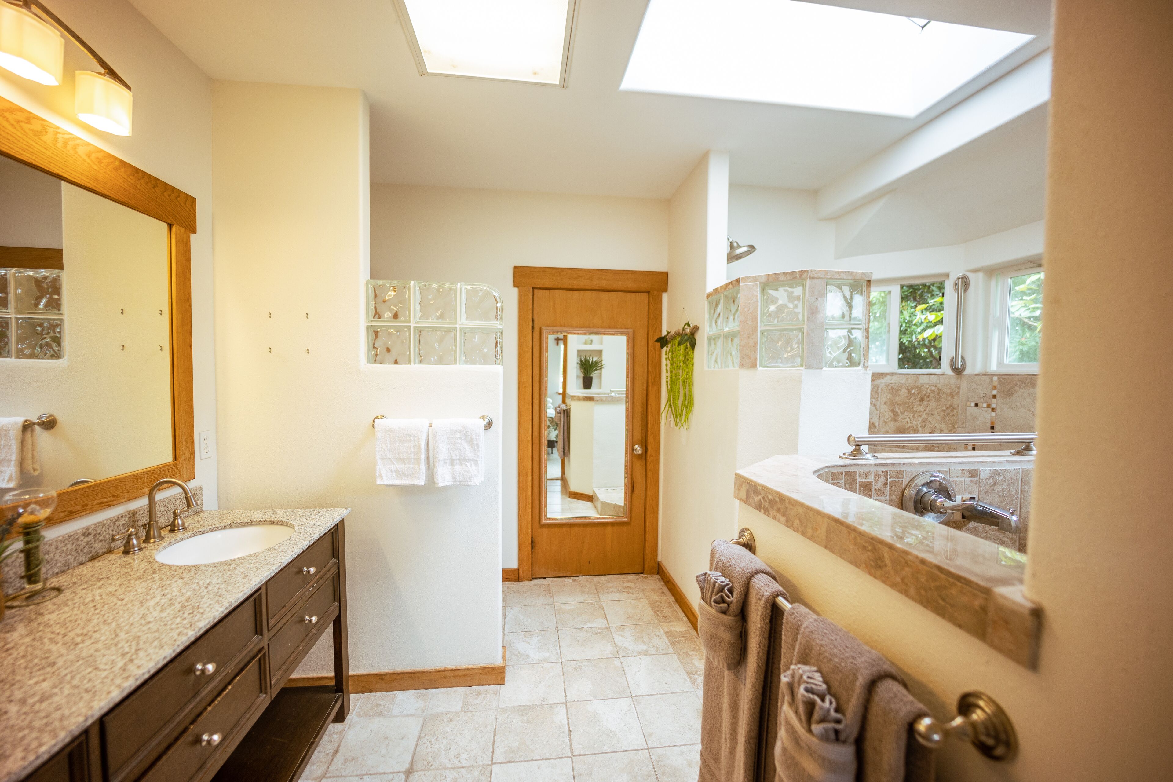 Un baño moderno con dos lavabos, un espejo grande y un tragaluz.