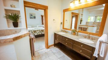 Une salle de bain avec deux lavabos, un grand miroir et une plante en pot.