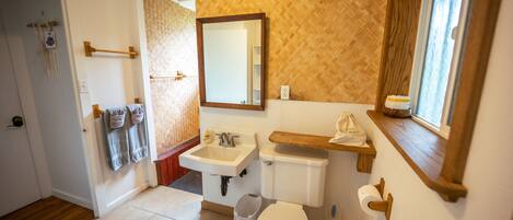 A bathroom with a wooden floor, a sink, a toilet, and a mirror.