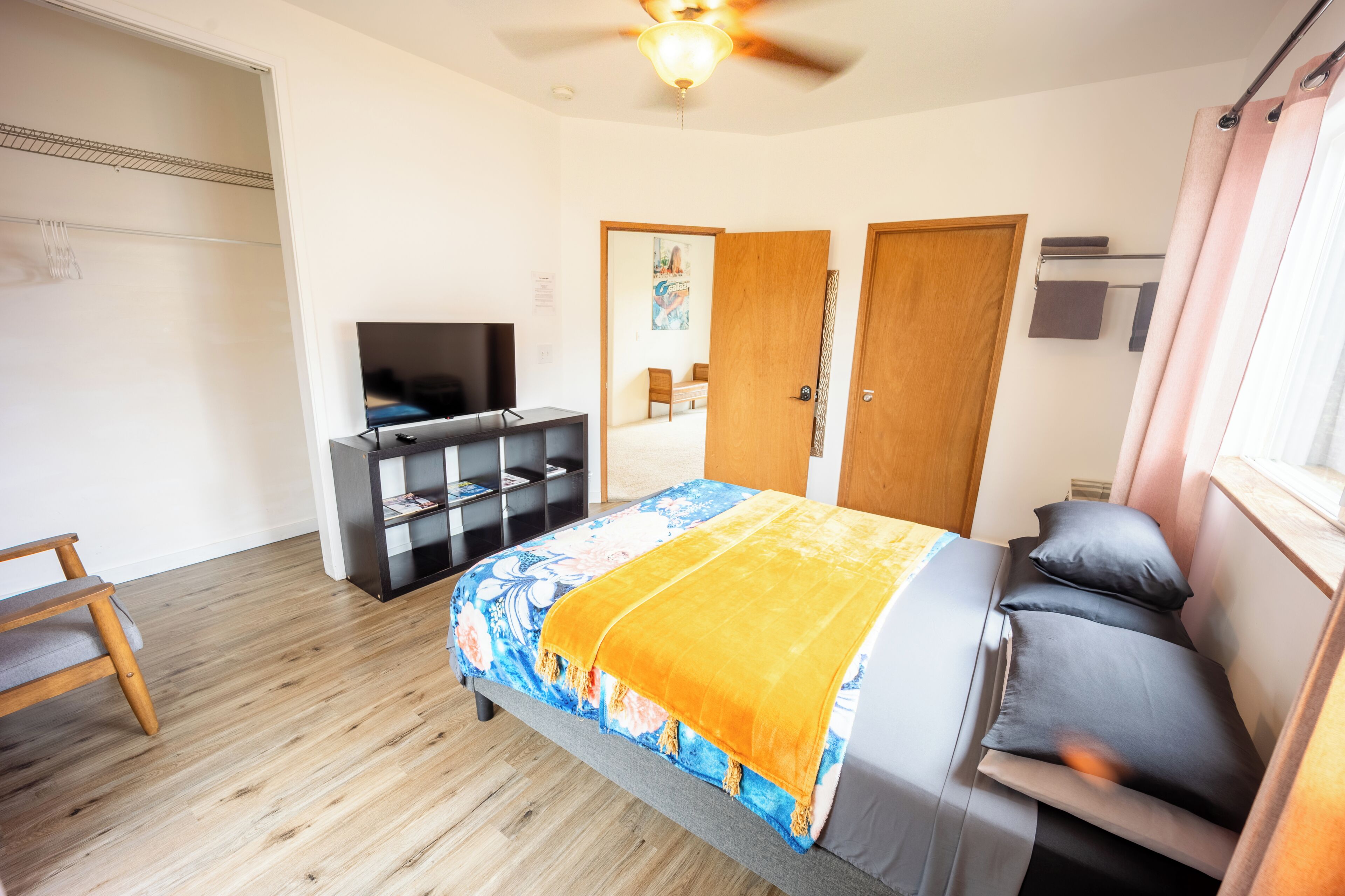 A bedroom with a bed, a TV, a wardrobe, and a ceiling fan.