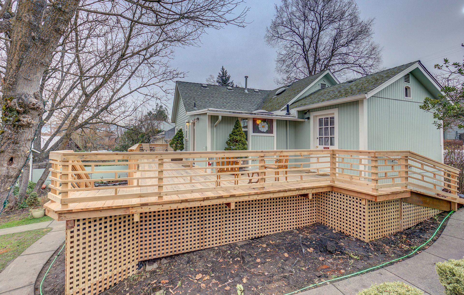 A house with a wooden deck and a green roof.