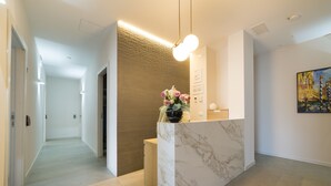 A reception area with a marble counter, a wall-mounted light fixture, and a painting on the wall. - Garda Room (Peschiera del Garda)