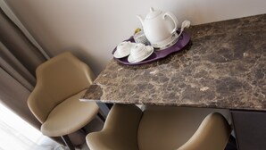 A dining area with a marble table, two beige chairs, and a white teapot with cups and saucers on a purple tray. - Garda Room (Peschiera del Garda)