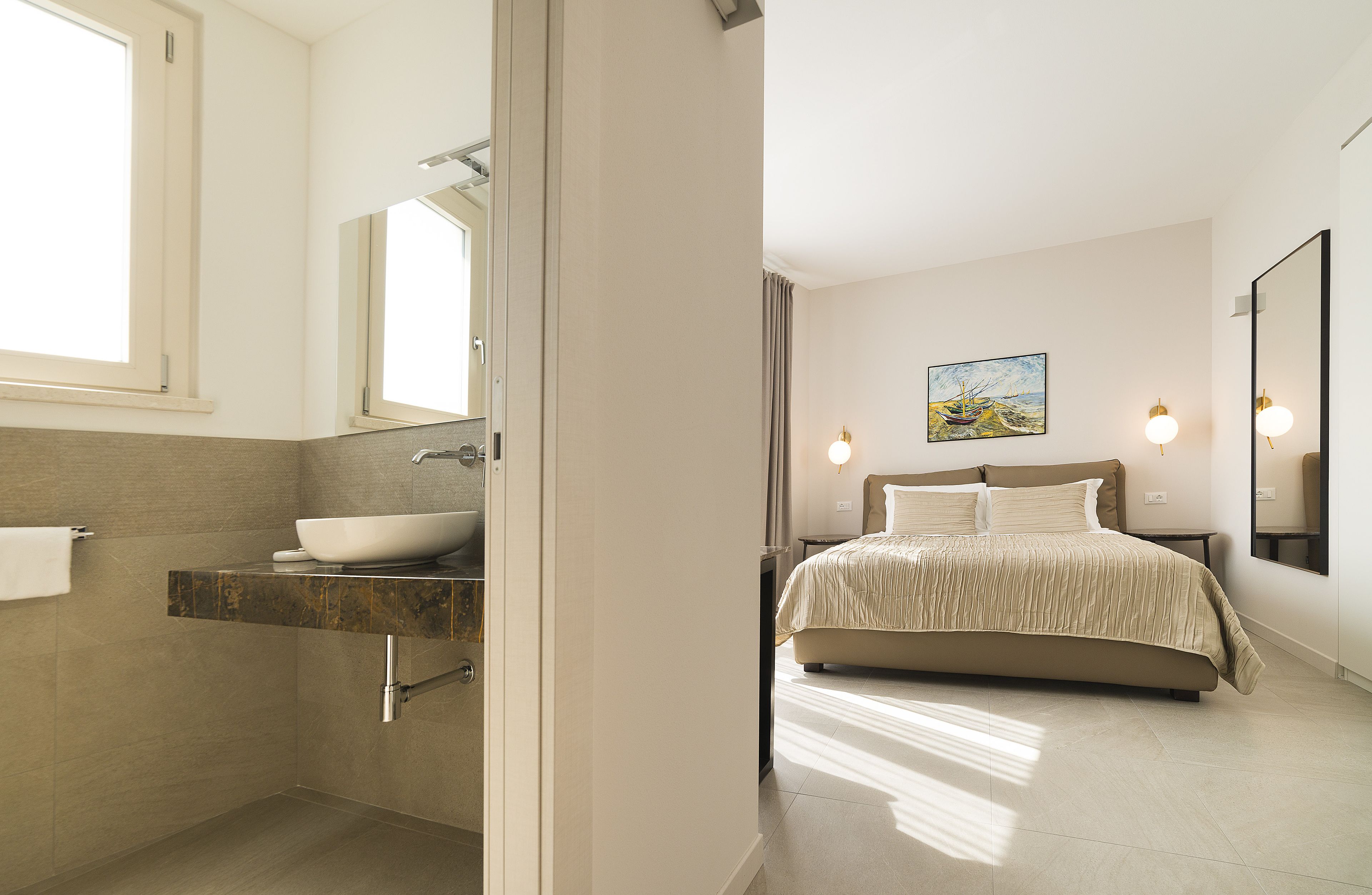 A modern bathroom with a large sink, mirror, and a bed with a headboard.