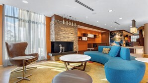 Una sala de estar moderna con chimenea de piedra, sillón de cuero, sofá azul y una mesa de centro redonda.