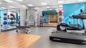 Un gimnasio con equipo de cardio, máquinas de pesas y pelotas de ejercicio.