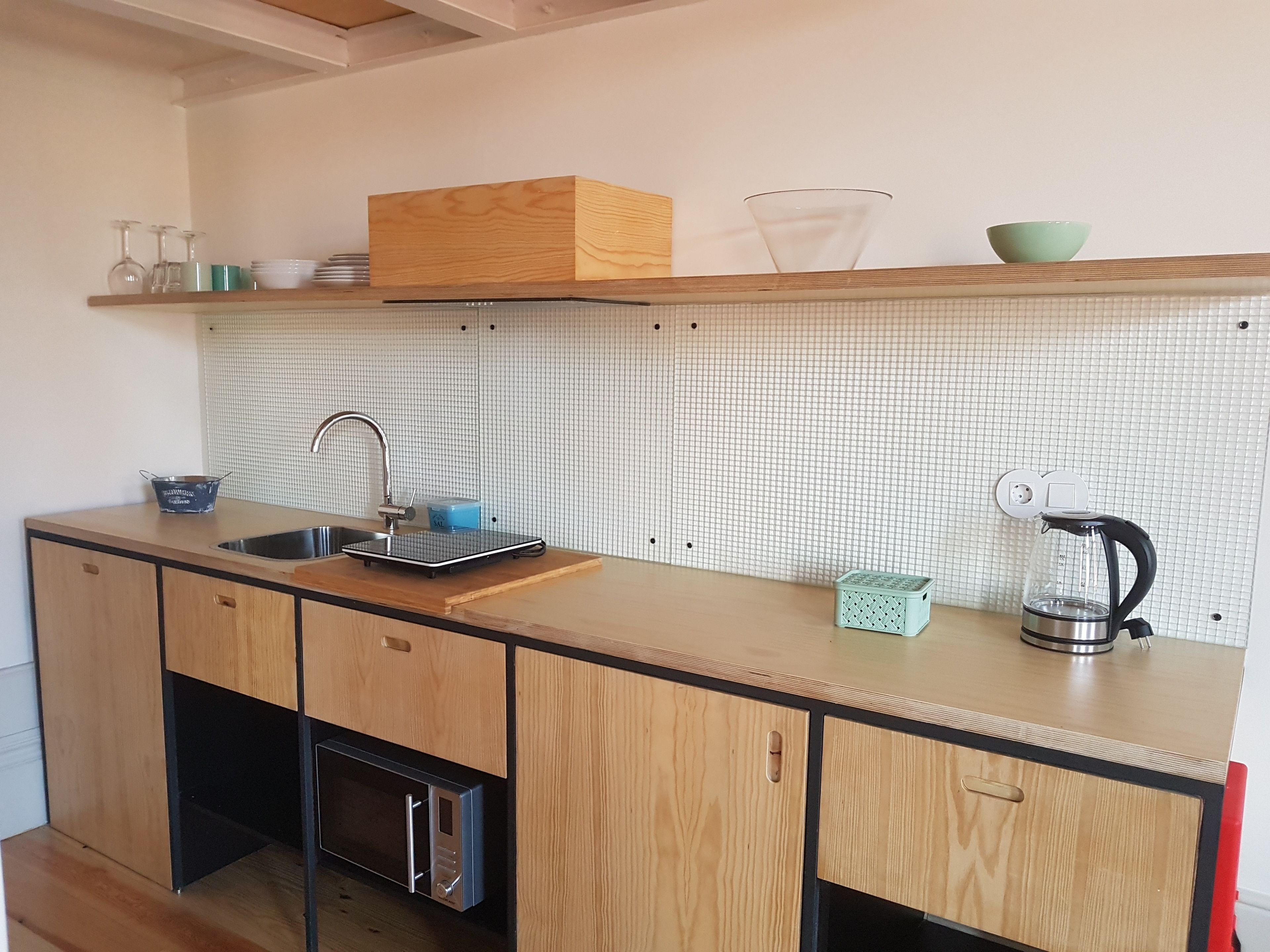 A kitchen with wooden cabinets, a sink, a microwave, and a coffee maker.