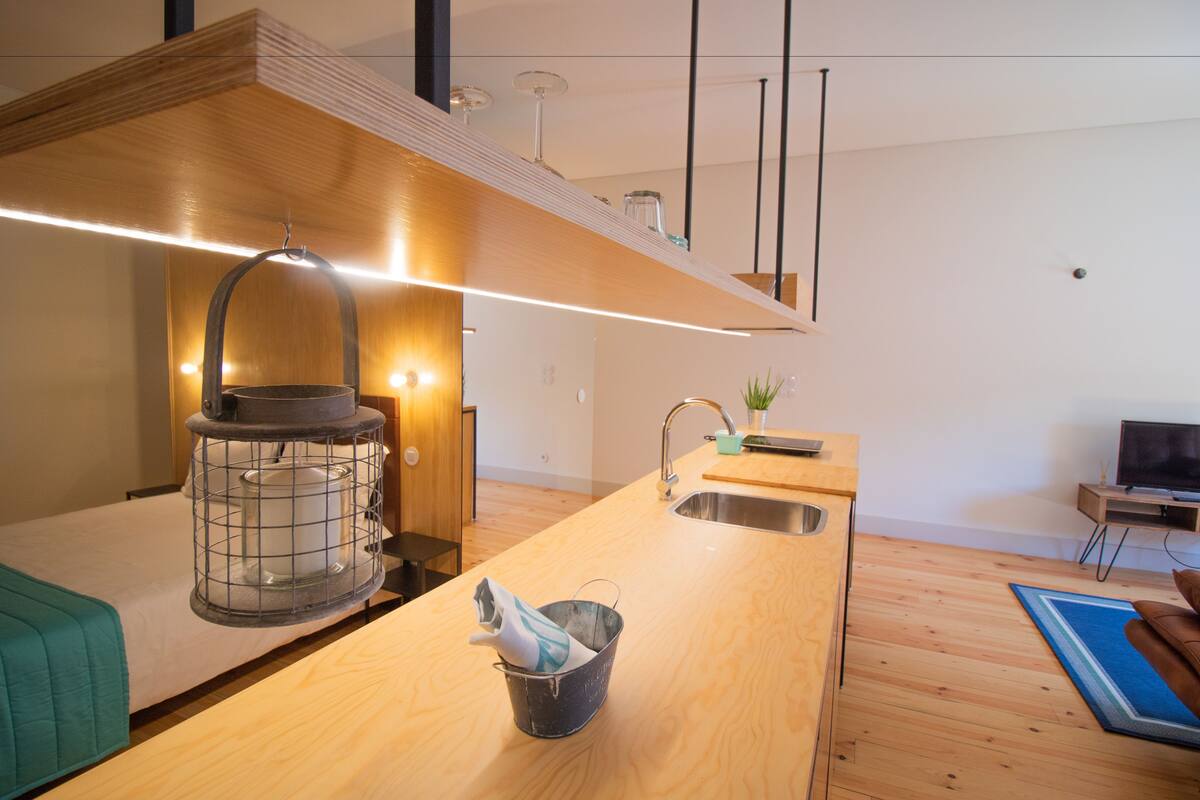 A modern kitchen with wooden countertops, a hanging pot rack, and a built-in sink.