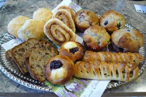 A variety of baked goods on a tray, including muffins, scones, and a pastry with a lattice crust.