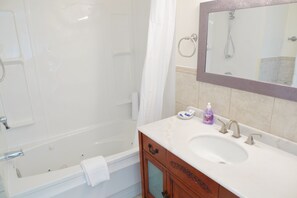 A bathroom with a bathtub, a sink, a mirror, and a shower.