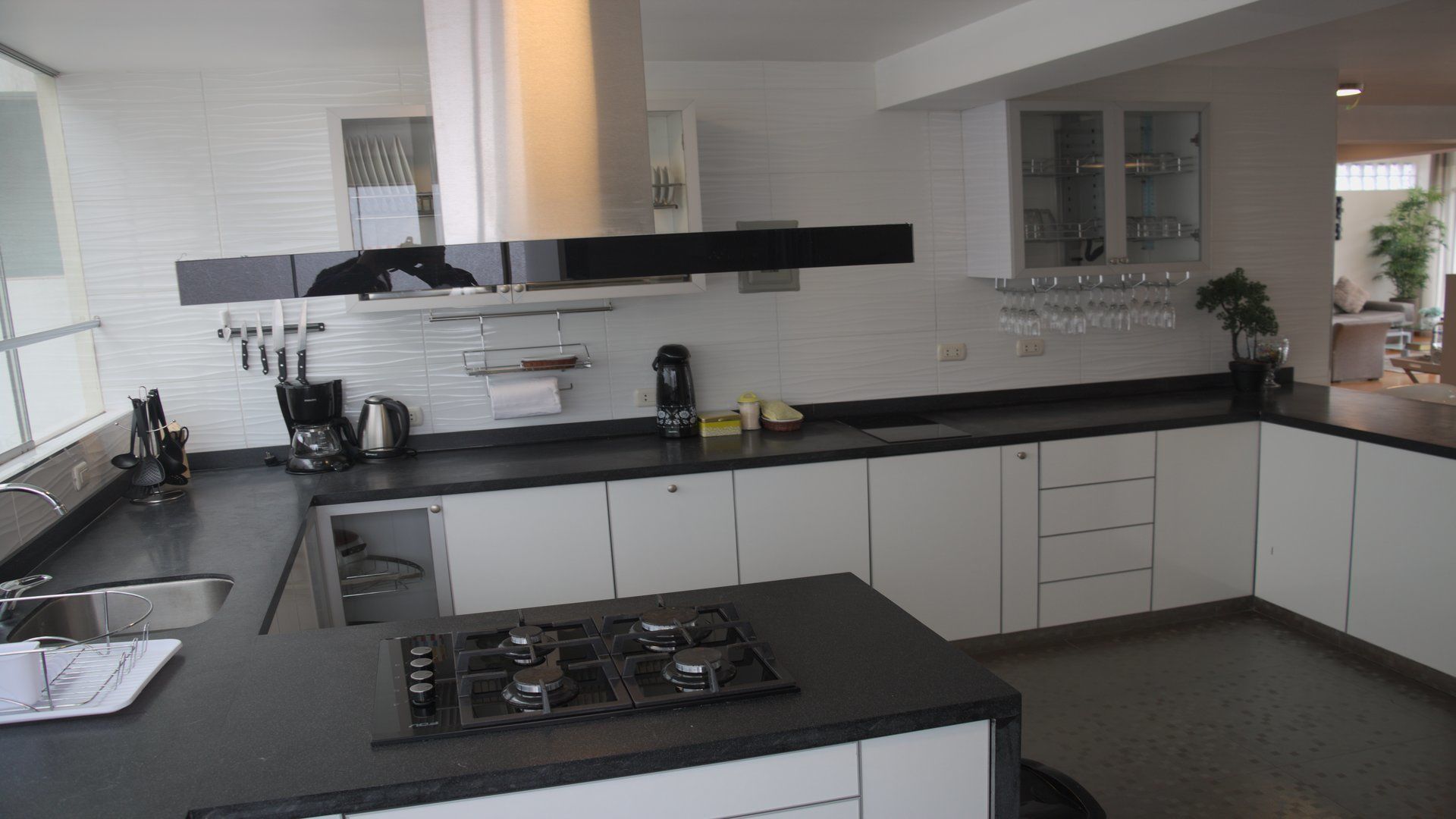A modern kitchen with white cabinets, a black countertop, and stainless steel appliances.