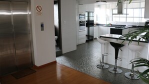 Una cocina moderna con electrodomésticos de acero inoxidable, una barra y un ascensor visible.