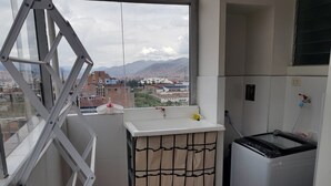Cocina compacta con ventana que da a un paisaje urbano, lavadora y tendedero.