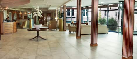 En rummelig lobby med receptionsdisk, siddeområde og store vinduer med udsigt til det fri.