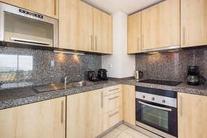 Una cocina con encimeras de granito, electrodomésticos de acero inoxidable, armarios de madera y horno integrado.