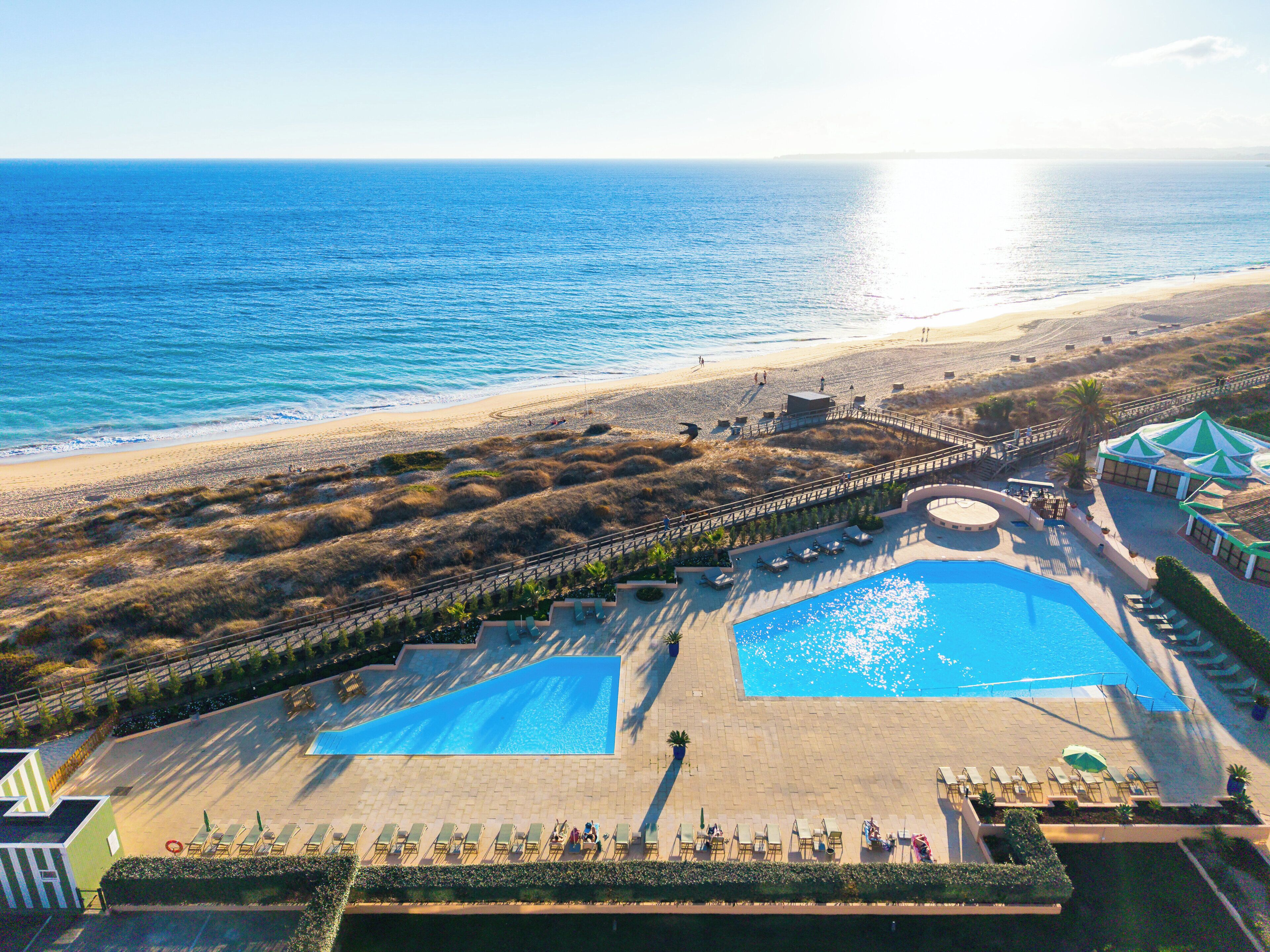A resort with a large pool, beach access, and a view of the ocean.