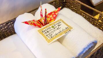 A basket containing neatly folded white towels with a decorative red and yellow paper attached.
