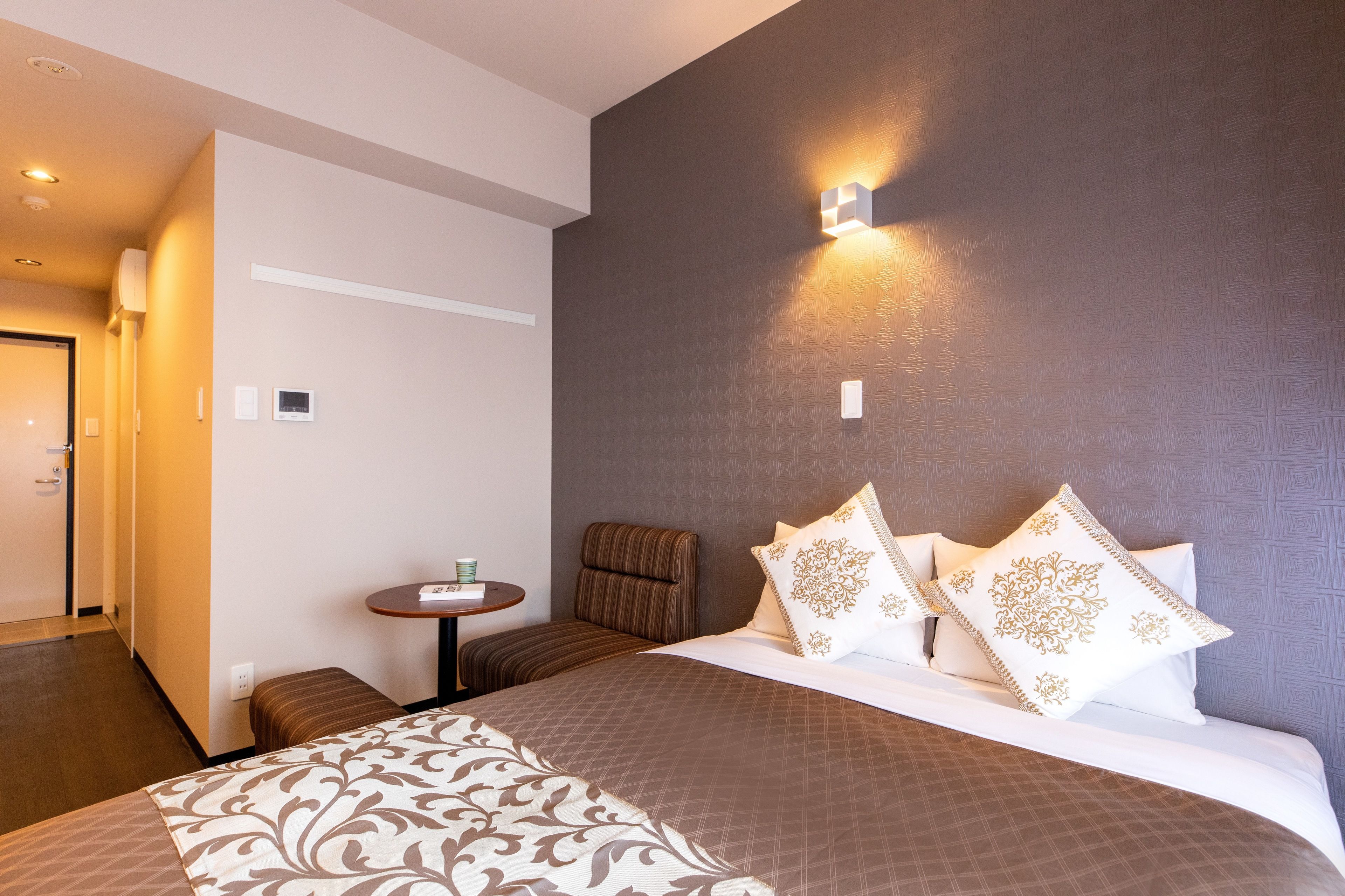 A hotel room with a large bed, a small table, and a chair.