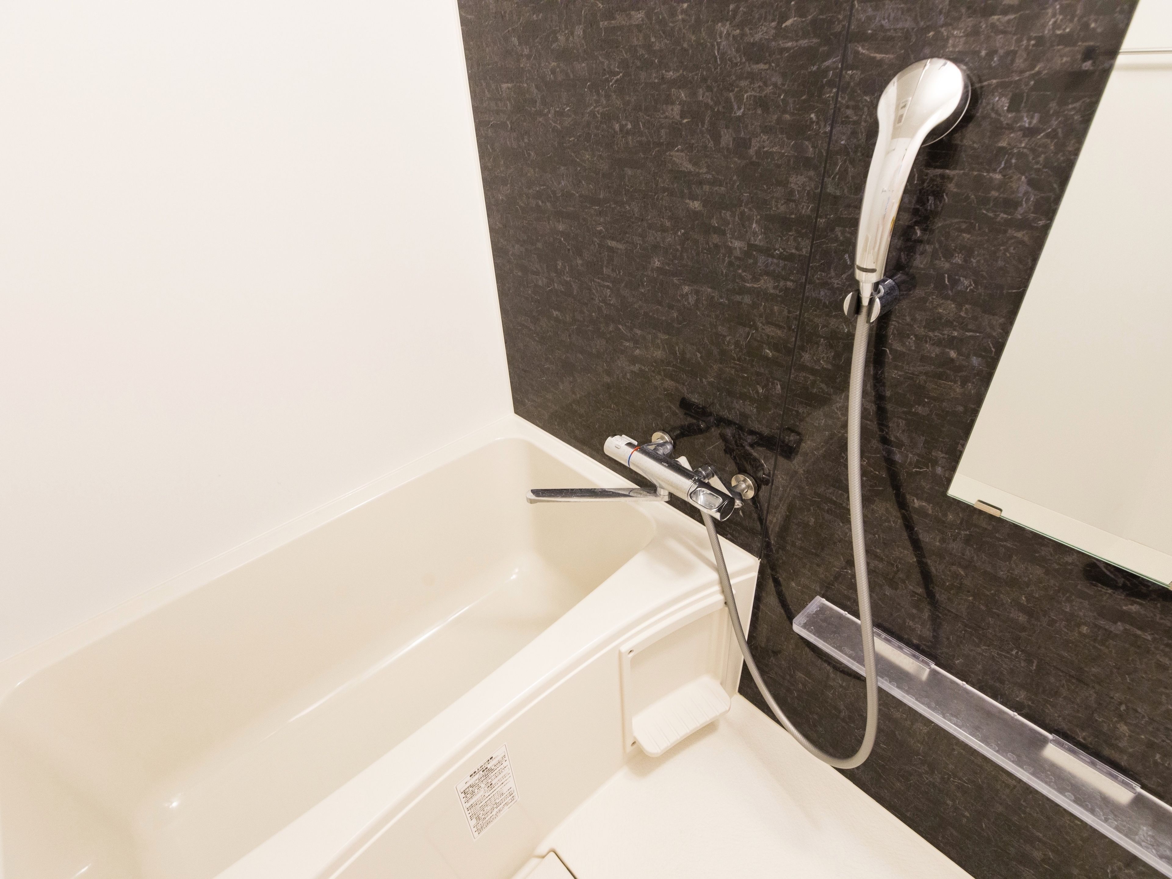A bathroom with a bathtub, a shower, and a mirror.
