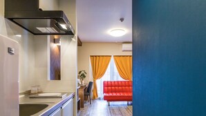 Une cuisine moderne dotée d’un four encastré, un coin repas avec un canapé rouge et une vue sur le salon.
