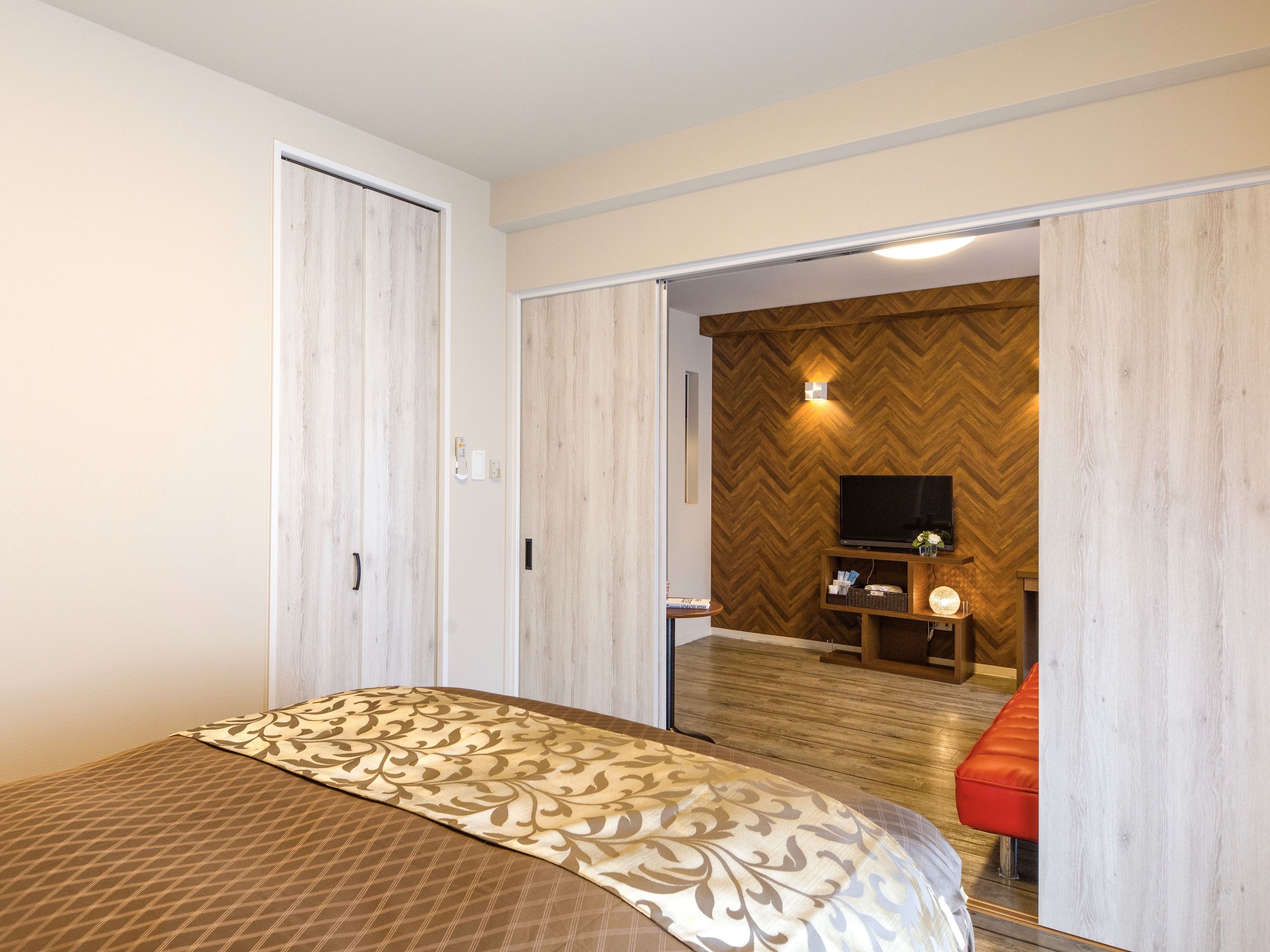 Una habitación de hotel con una cama, un televisor y una pared de madera con motivo de espiga.