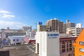 Eine Stadtansicht mit verschiedenen Gebäuden, darunter ein markantes weißes Gebäude mit einer Beschriftung in japanischer Schrift.
