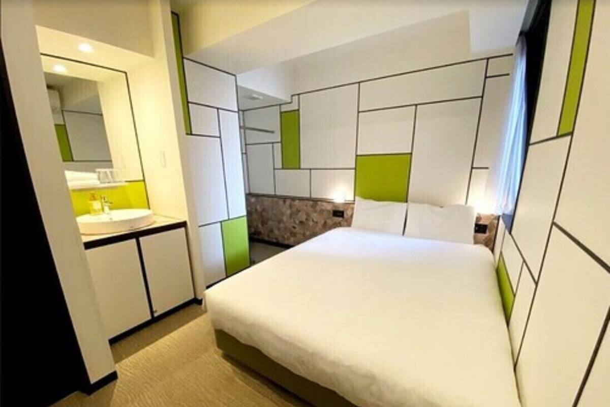 Une chambre d’hôtel moderne avec un grand lit, une salle de bain avec un miroir et un mur d’accent de couleur verte.