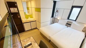 Ein Hotelzimmer mit einem Bett, einem kleinen Schreibtisch, einem Spiegel und einem Fenster.