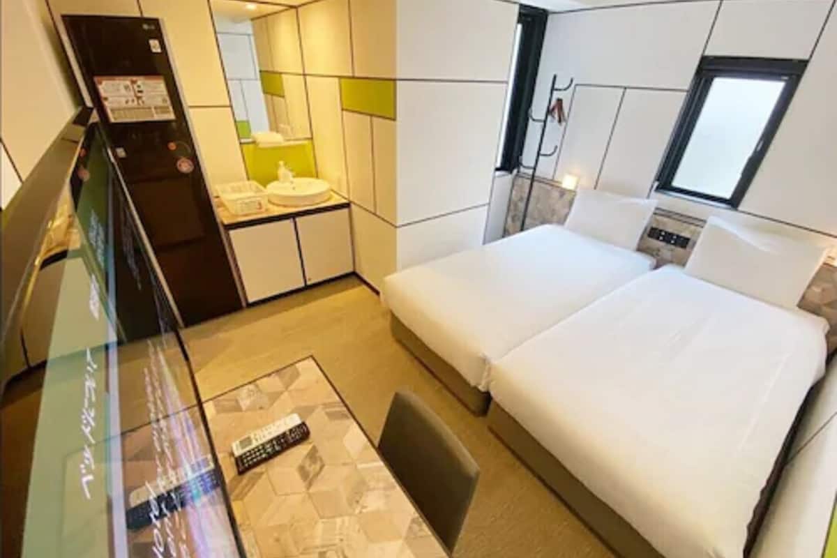 Une chambre d’hôtel avec un lit, un petit bureau, un miroir et une fenêtre.