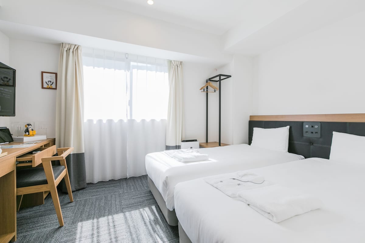 Habitación de hotel con dos camas, un escritorio y una silla.