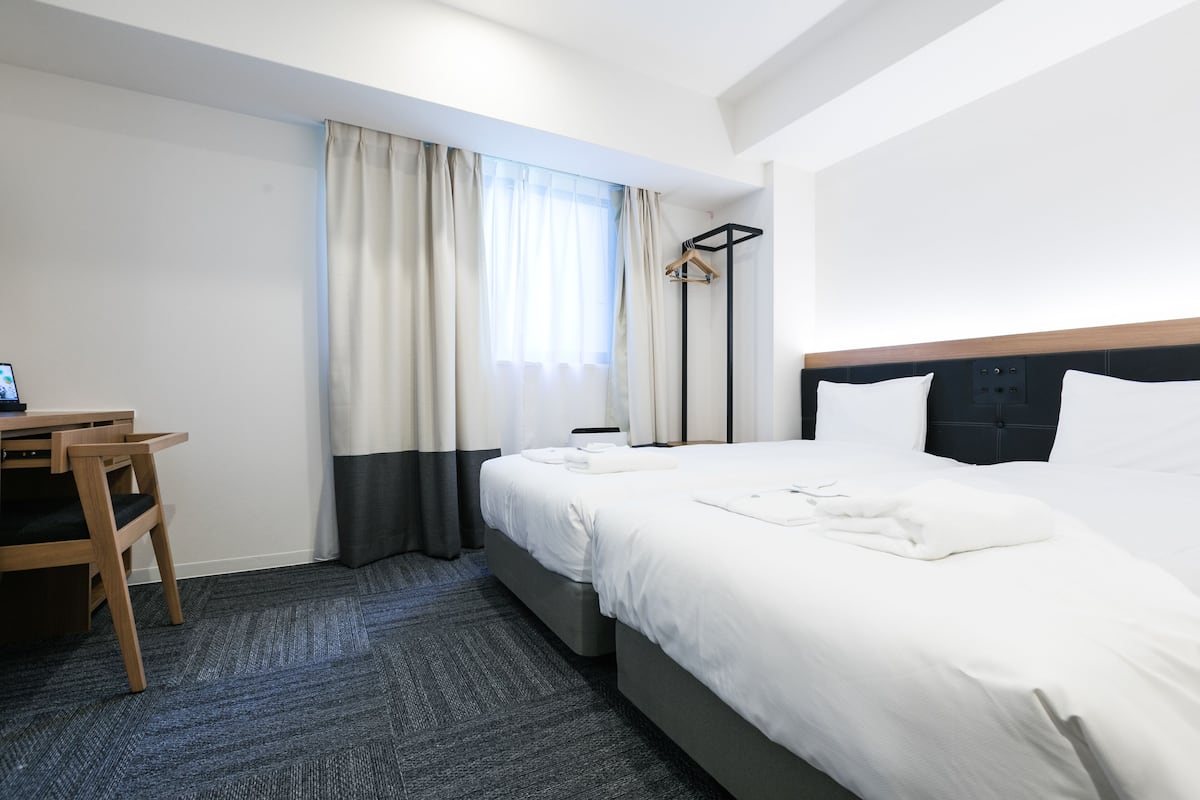 Una habitación de hotel con cama, escritorio y silla.