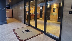 Een hotel lobby met een receptiebalie, glazen deuren en een houten vloer.
