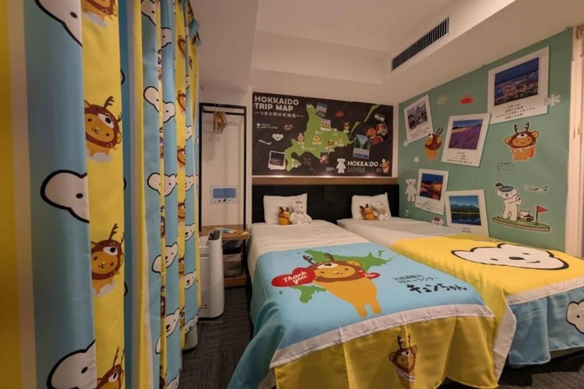 Habitación de hotel con dos camas, un mapa en la pared y una ventana con cortinas.
