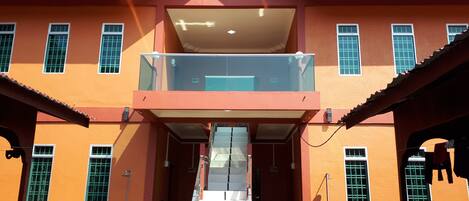 A two-story building with a balcony on the upper floor, a covered entrance, and a small outdoor seating area.