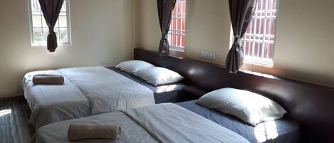 A room with two beds, each with a pillow and a rolled towel.