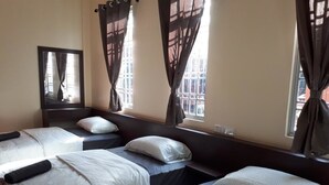 A hotel room with three beds, each with white bedding and a pillow. There is a window with curtains, and a mirror on the wall. - Juara Mutiara Resort (Tioman Island)