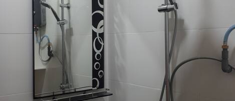 A bathroom with a black sink, a mirror, and a shower with a handheld showerhead.