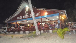 A restaurant with a covered outdoor seating area and a sign reading "JUARA MUTIARA CAFE". - Juara Mutiara Resort (Tioman Island)
