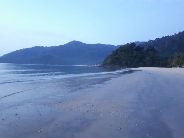 A beach with a sandy shore and a mountain in the background.