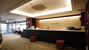 Un área de recepción con mostrador, un cartel que dice "ARK HOTEL" y una alfombra estampada.