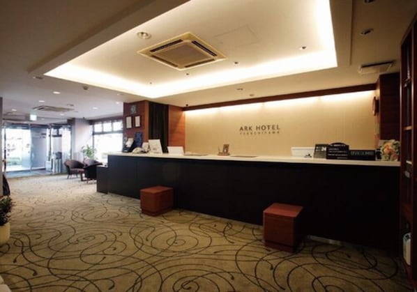A reception area with a counter, a sign reading "ARK HOTEL," and a patterned carpet. - Fukuchiyama Ark Hotel (Fukuchiyama)
