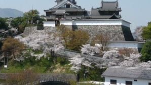 Un castillo japonés tradicional con varios niveles, muros de piedra y un puente que conduce a la entrada.