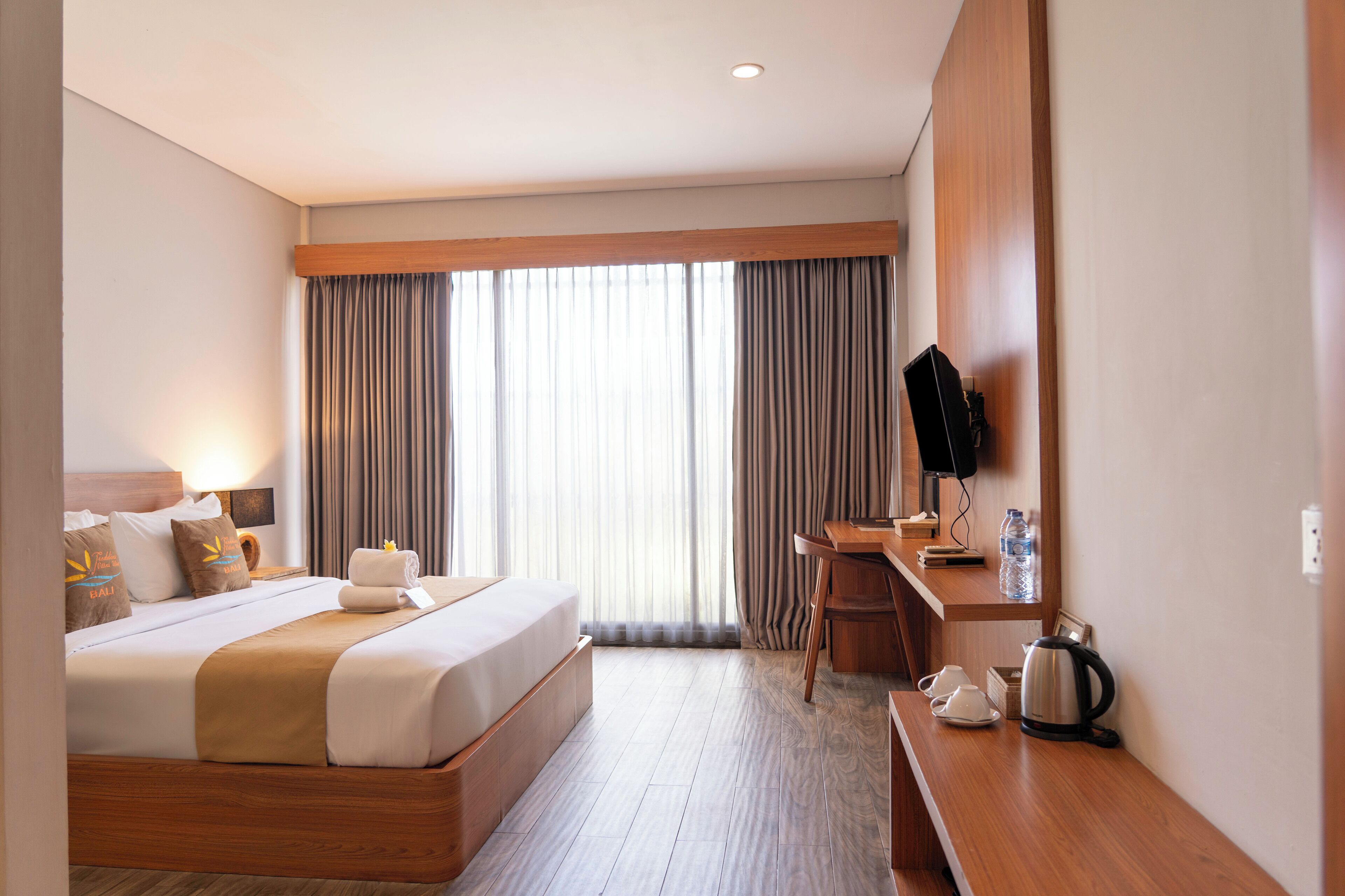 Ein Hotelzimmer mit einem großen Bett, einem Schreibtisch mit Stuhl, einem Fernseher und einer Kaffeemaschine.